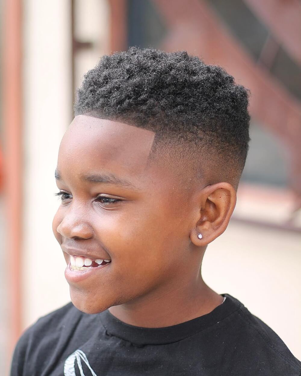 Ein High Skin Fade-Haarschnitt mit Wendungen für kleine schwarze Jungen