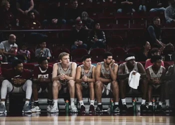 Ein Foto von LOGAN WEAVER | @LGNWVR auf Unsplash zeigt eine Gruppe von Basketballspielern auf der Bank