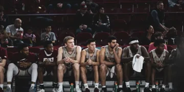 Ein Foto von LOGAN WEAVER | @LGNWVR auf Unsplash zeigt eine Gruppe von Basketballspielern auf der Bank