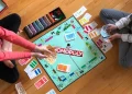 Monopoly Brettspiel auf dem Boden mit Spielern, Geldscheinen und Karten während eines Spieleabends