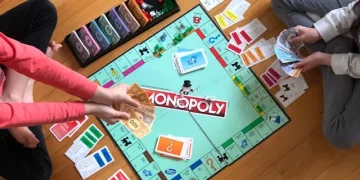 Monopoly Brettspiel auf dem Boden mit Spielern, Geldscheinen und Karten während eines Spieleabends