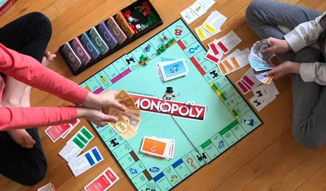 Monopoly Brettspiel auf dem Boden mit Spielern, Geldscheinen und Karten während eines Spieleabends