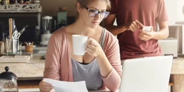 Selbstständige prüft Unterlagen für Kredit für Selbstständige am Laptop