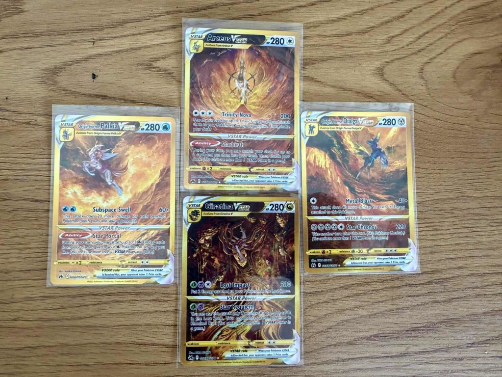 Vier Pokémon-Sammelkarten mit Arceus, Dialga, Palkia und Giratina nebeneinander.