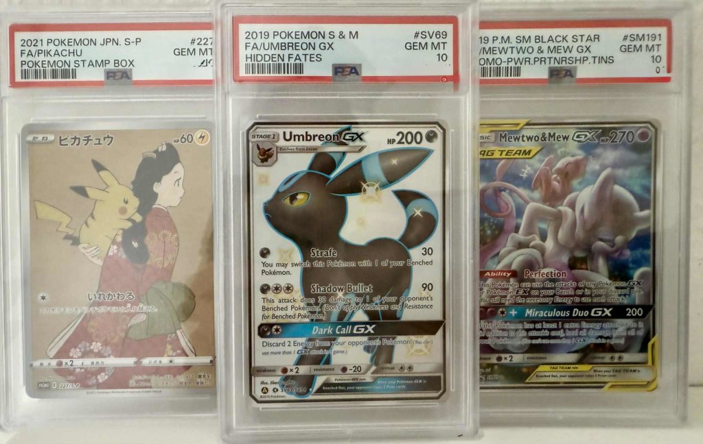 Drei Pokémon-Karten mit PSA-Bewertung 10: Pikachu, Umbreon GX und Mewtwo & Mew GX.