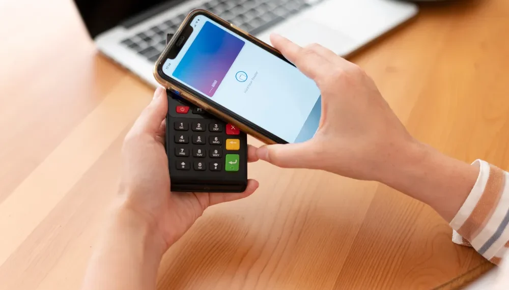 Person hält ein Smartphone und ein mobiles Zahlungsterminal in den Händen