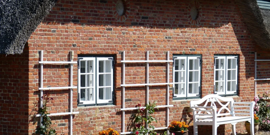 Immobilien-Flut auf Sylt: Warum plötzlich Hunderte Häuser zum Verkauf stehen 1 Reetdachhaus auf Sylt mit Klinkerfassade und weißer Sitzbank vor dem Gebäude