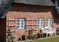 Reetdachhaus auf Sylt mit Klinkerfassade und weißer Sitzbank vor dem Gebäude