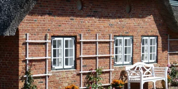 Reetdachhaus auf Sylt mit Klinkerfassade und weißer Sitzbank vor dem Gebäude