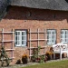 Immobilien-Flut auf Sylt: Warum plötzlich Hunderte Häuser zum Verkauf stehen 4 Reetdachhaus auf Sylt mit Klinkerfassade und weißer Sitzbank vor dem Gebäude