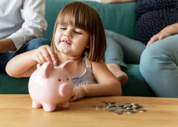 Kind wirft Münzen in ein Sparschwein – Symbolbild für die Frühstartrente und staatlich geförderte Altersvorsorge für Kinder.