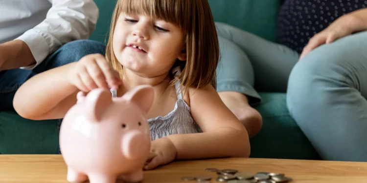 Kind wirft Münzen in ein Sparschwein – Symbolbild für die Frühstartrente und staatlich geförderte Altersvorsorge für Kinder.