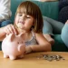 Frühstartrente: Der Staat zahlt 10 Euro für Kinder – daraus könnten 53.000 Euro werden 1 Kind wirft Münzen in ein Sparschwein – Symbolbild für die Frühstartrente und staatlich geförderte Altersvorsorge für Kinder.